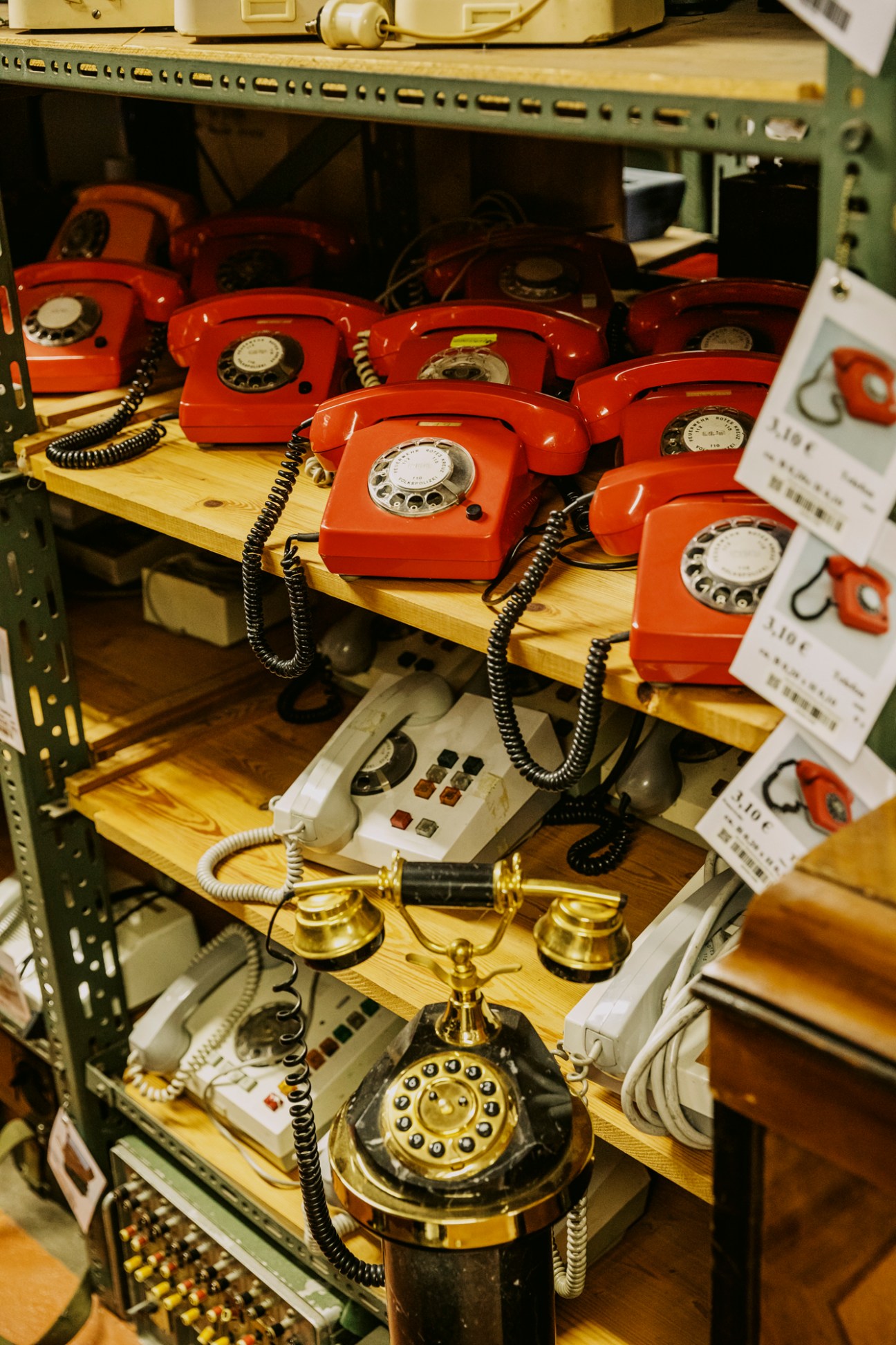 Collection of vintage telephones from different eras arranged on shelves in studio prop storage