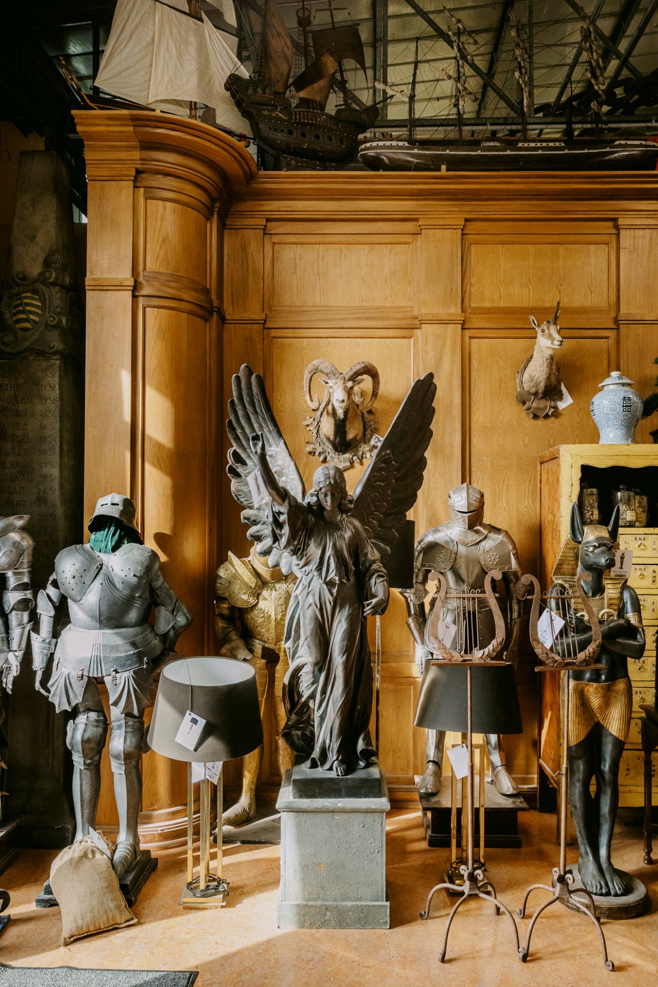 Diverse collection of props including statues, armor, and mounted taxidermy displayed in warehouse