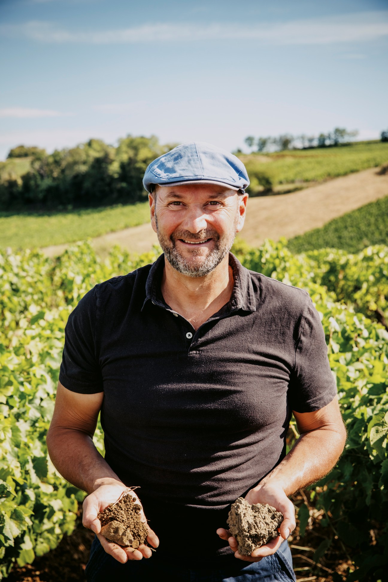 Winemaker Stéphane Tissot holding soil samples in his hands while standing in a vineyard