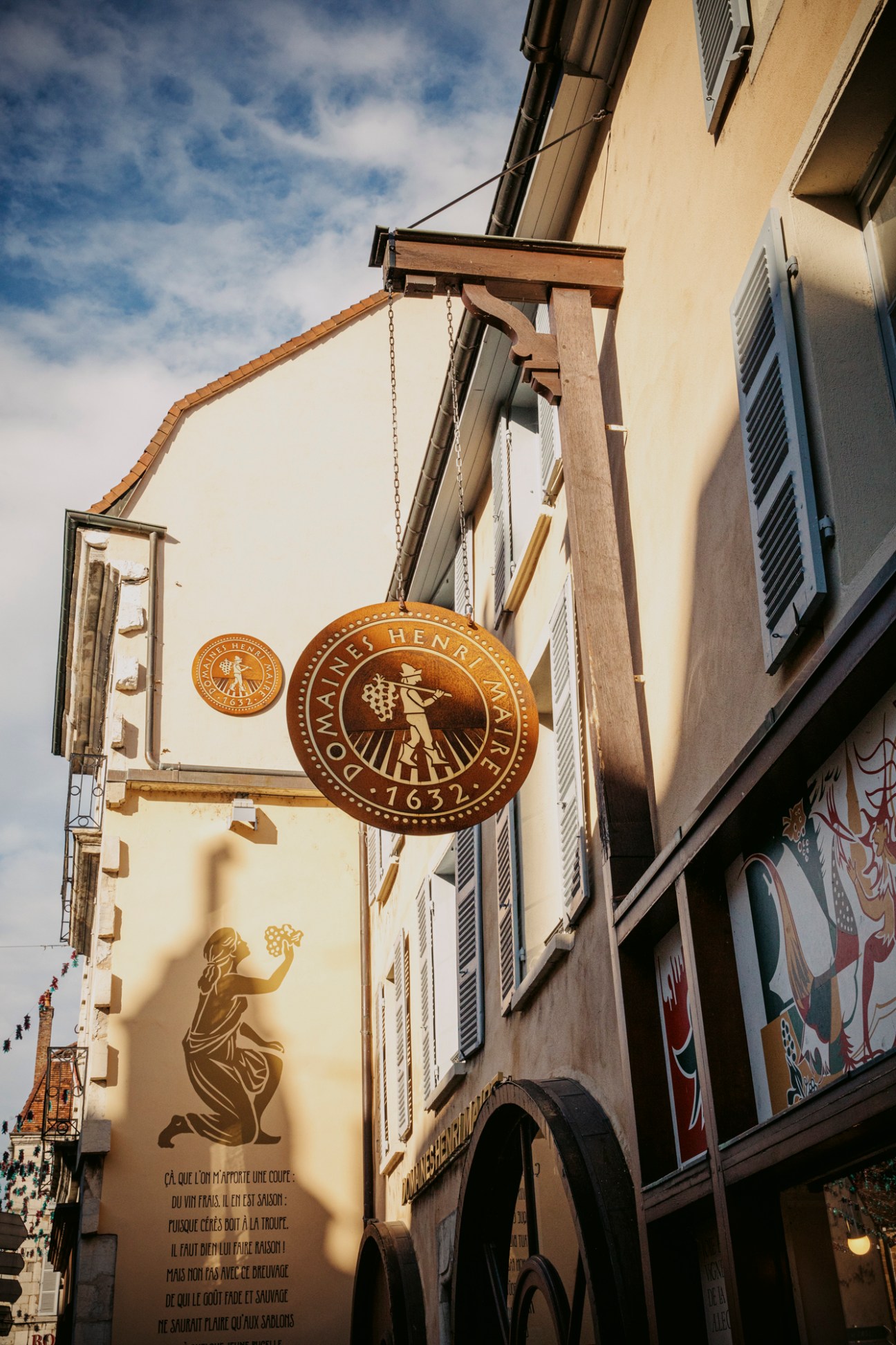 Traditional wooden wine shop sign hanging from building in Arbois, France
