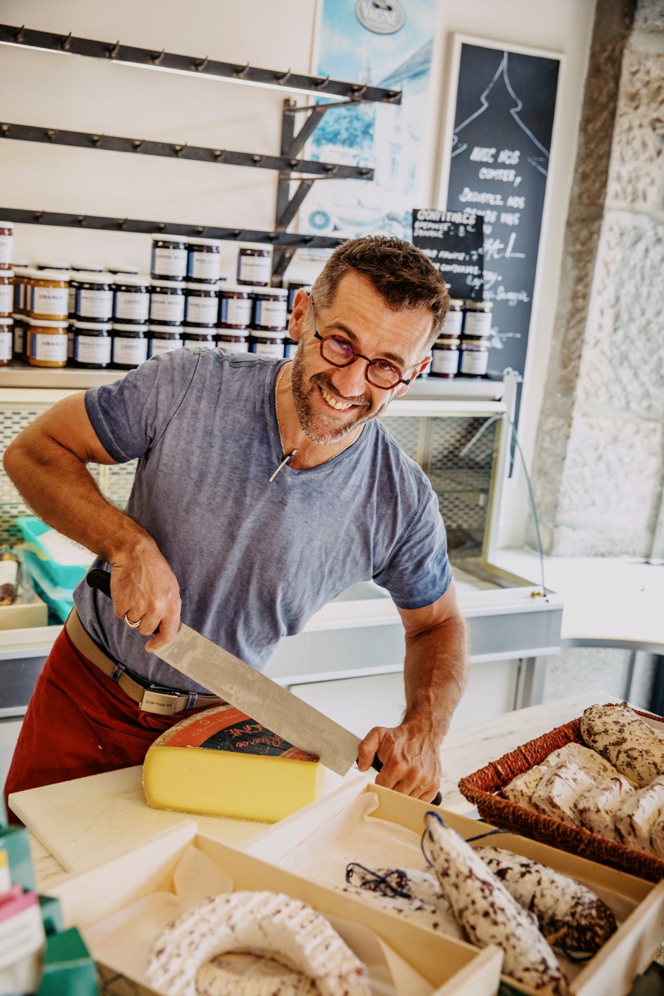 Person cutting a large wheel of comte cheese at Epicurea fromagerie in Poligny