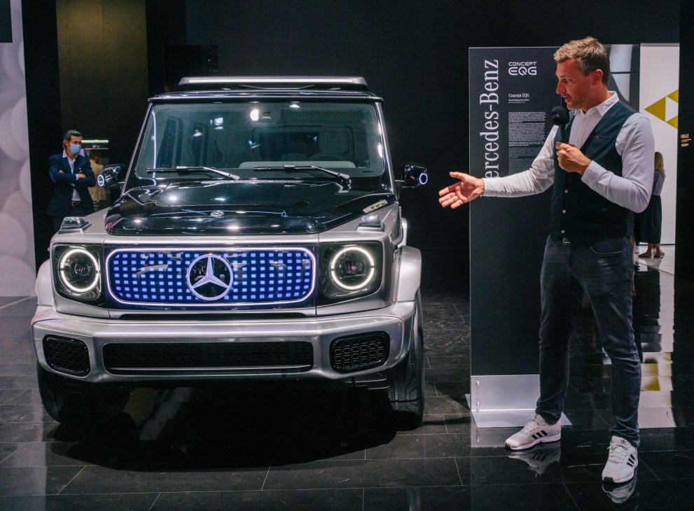 Man presenting Mercedes-Benz EQG concept car with illuminated grille at motor show
