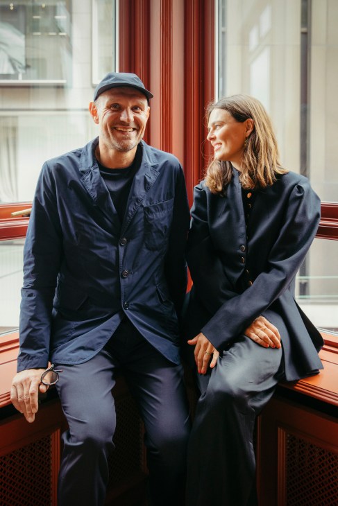 Rolf and Mette Hay sitting together smiling in navy clothing by a window