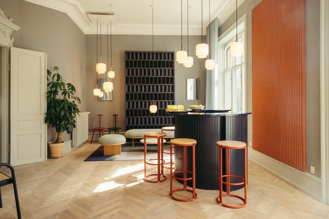 Modern interior with curved black counter, pendant lights, orange bar stools and terracotta accent wall