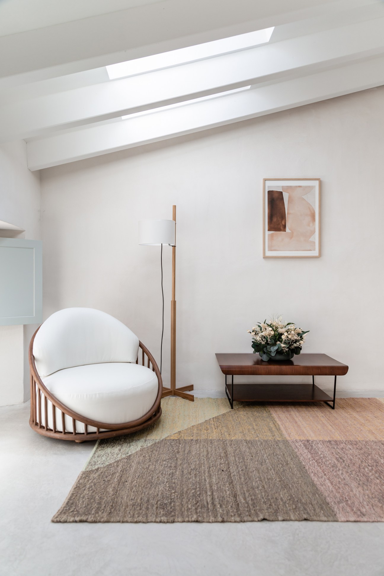 Modern hotel room interior with curved rattan chair, exposed ceiling beams, and neutral color palette