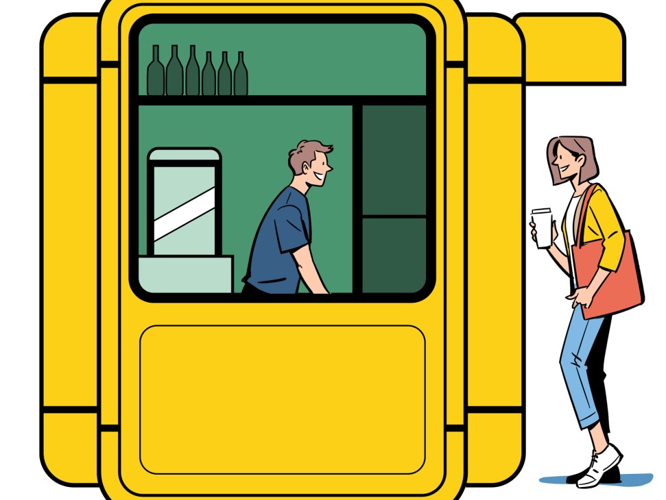 Yellow modernist kiosk with geometric design featuring a vendor inside and customer outside