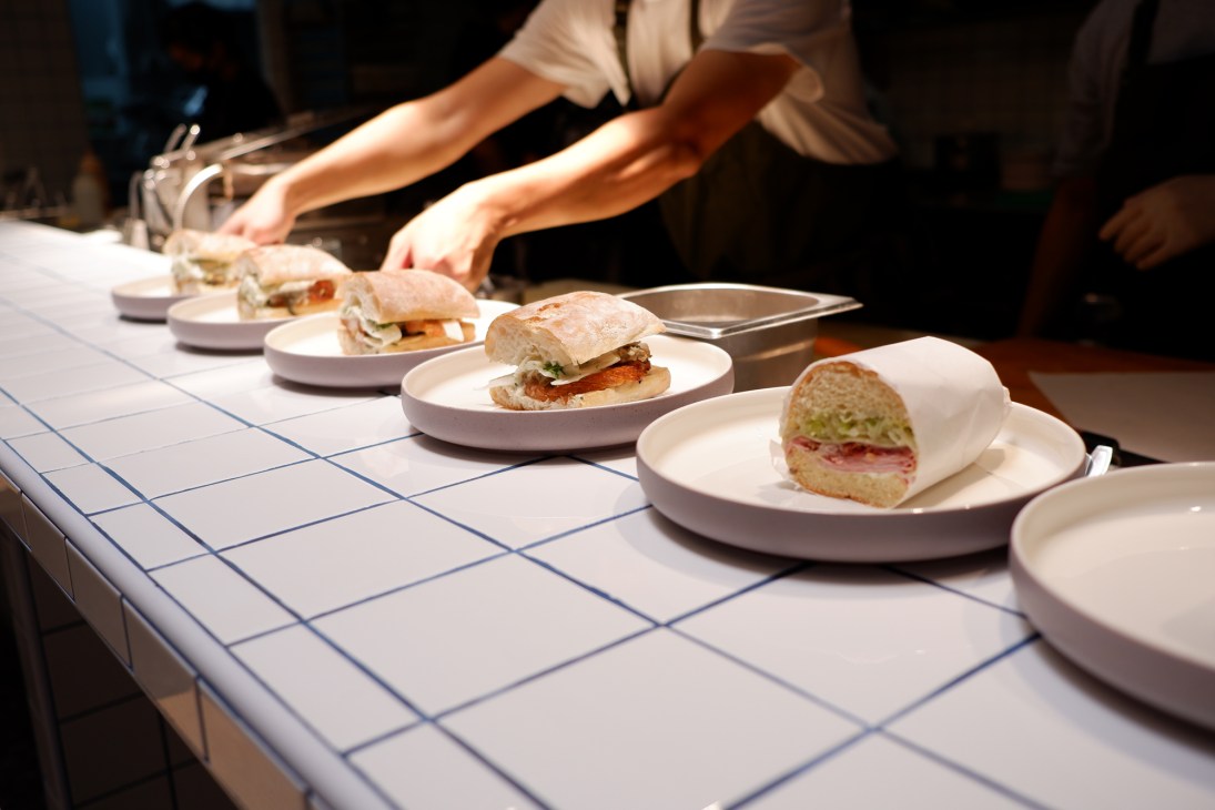 Chef plating Cuban sandwiches on white plates at Onda restaurant counter in Singapore