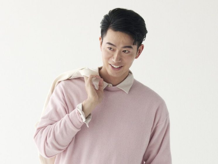 Man wearing pink jumper over white shirt with beige trousers and trainers