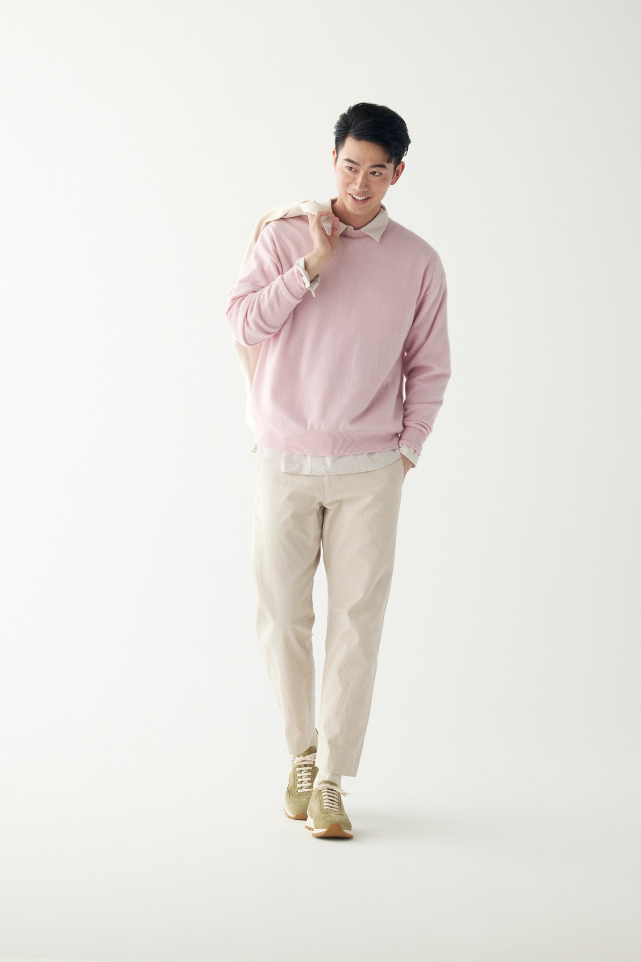 Man wearing pink jumper over white shirt with beige trousers and trainers