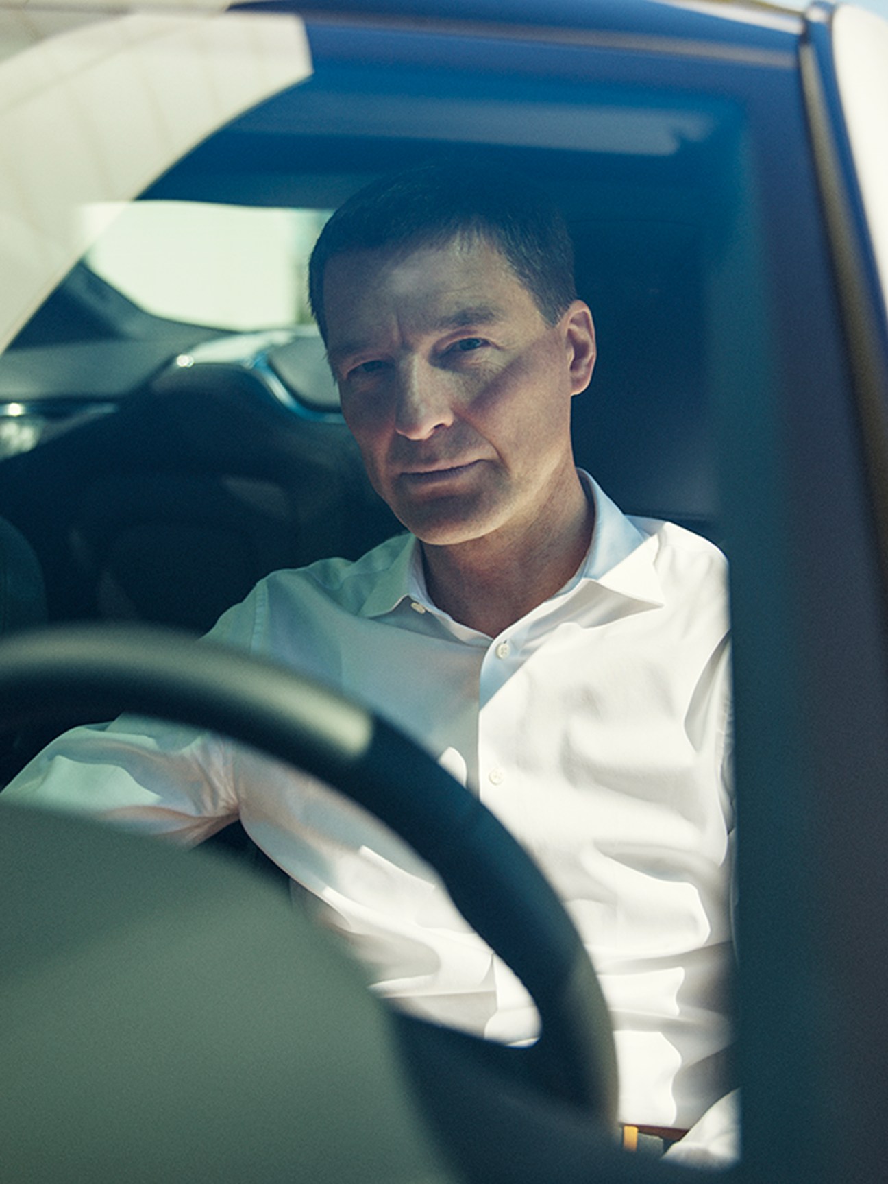 Thomas Ingenlath sitting in driver's seat of car wearing white button-up shirt