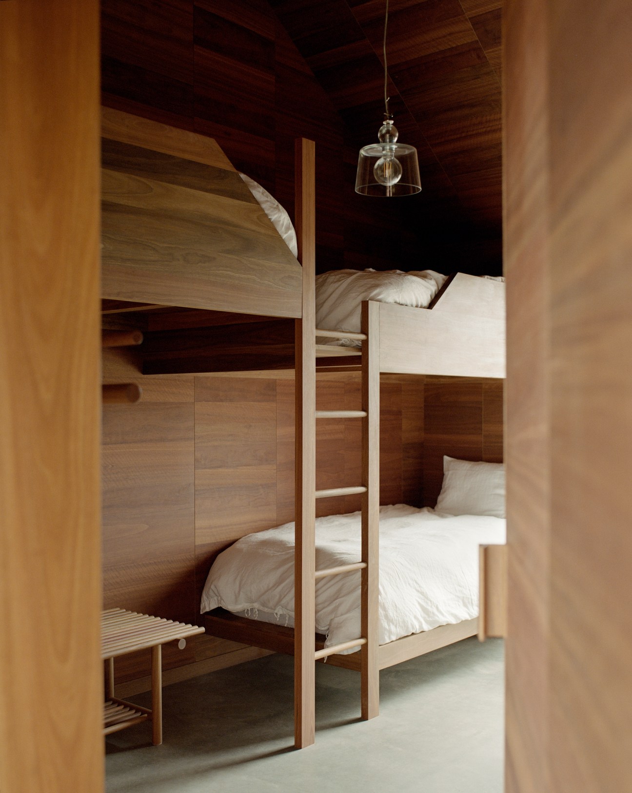 Built-in timber bunk beds with ladder and pendant light in bedroom with wooden ceiling beams