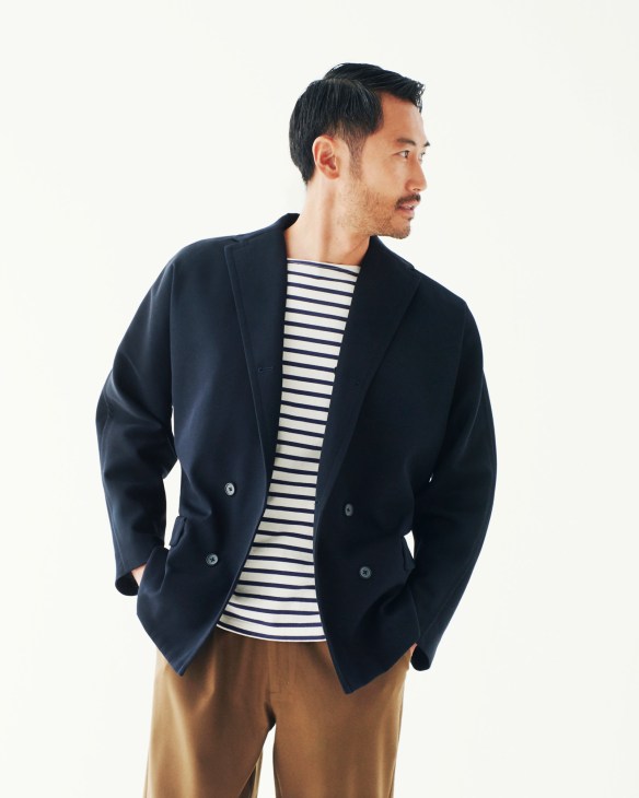 Man wearing a navy double-breasted blazer by Tomorrowland over a striped shirt and tan trousers.