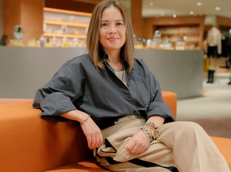 Blondie Tsang, president of Lane Crawford and Joyce, sits on an orange sofa in a modern retail space with warm lighting.