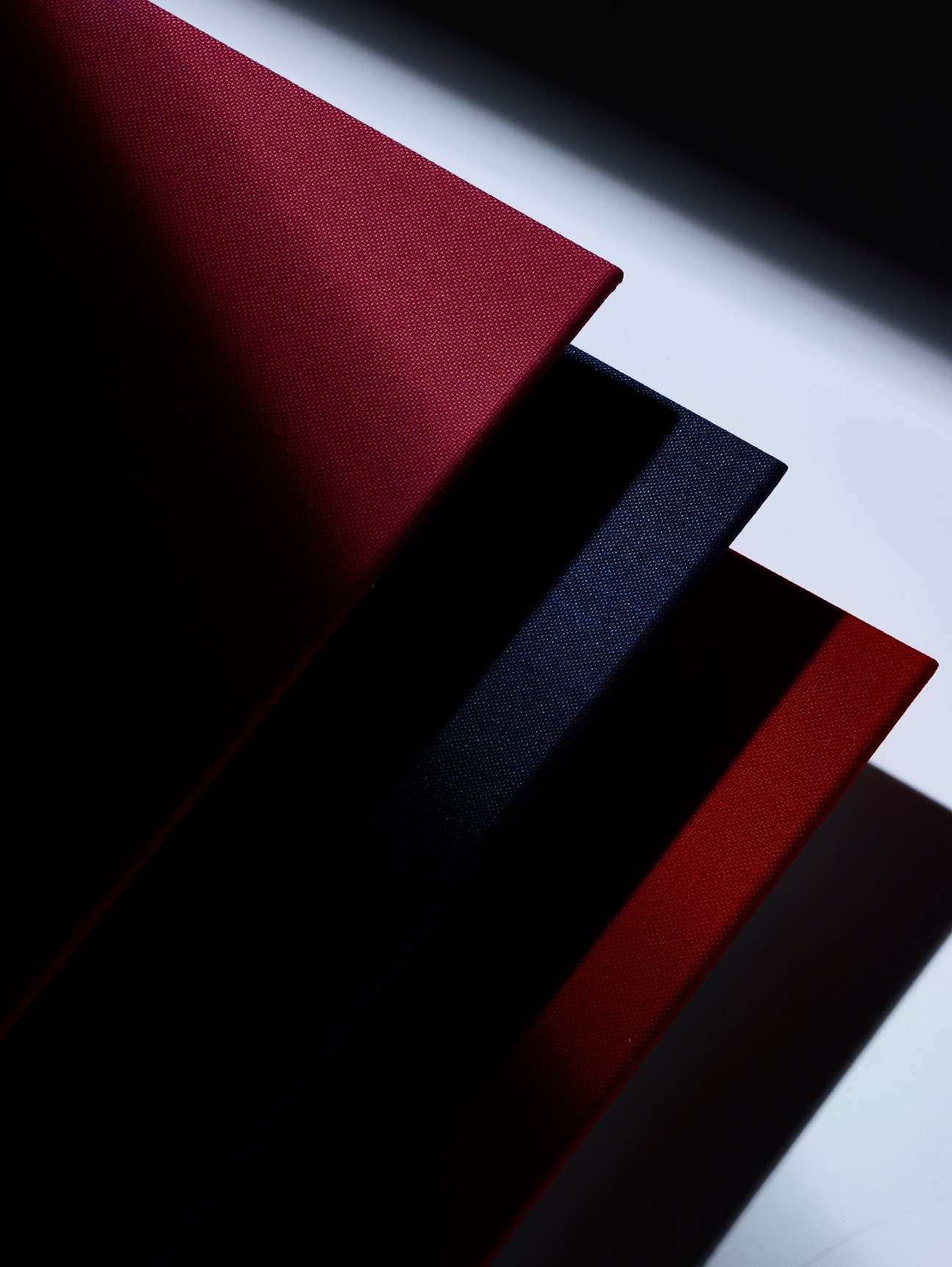 Stacked fabric acoustic panels from Kvadrat in burgundy, navy, and red colors arranged in geometric layers