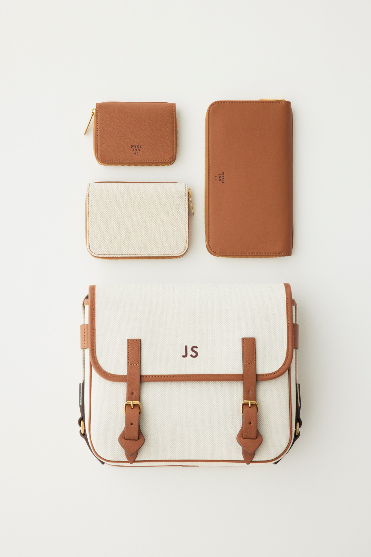 Collection of brown leather accessories including wallets and cream canvas bag with JS monogram by L/Uniform