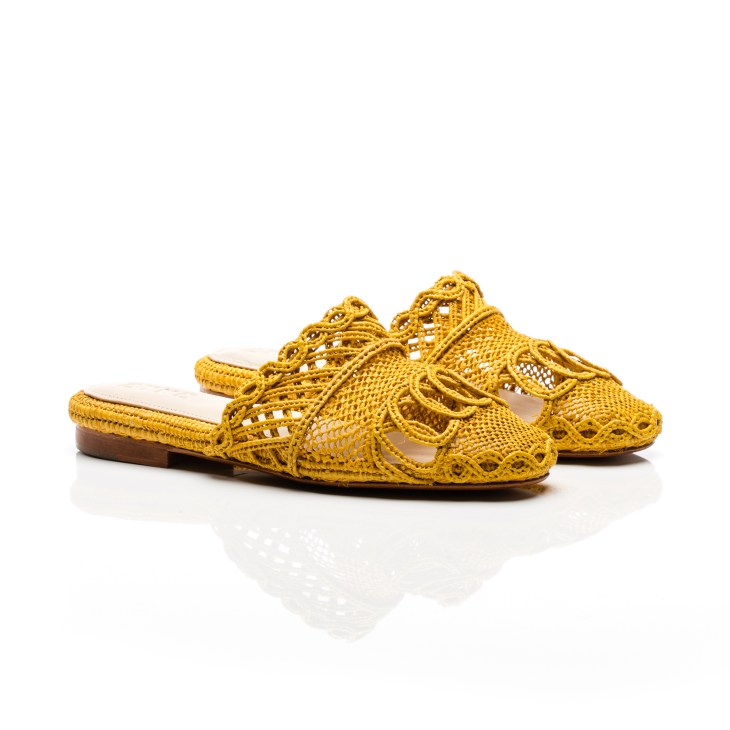 Pair of yellow Zyne raffia slippers with intricate woven patterns and flat sole.