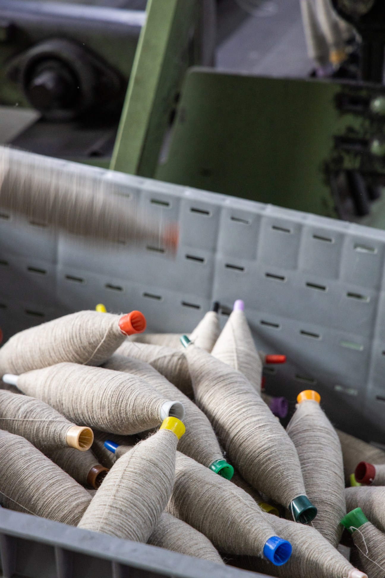 Colorful thread spools with plastic caps arranged in container at textile manufacturing facility