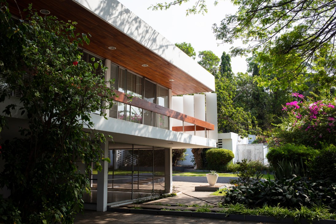 Scott House, built in 1961 - modern white building with horizontal slats and overhanging roof surrounded by lush greenery