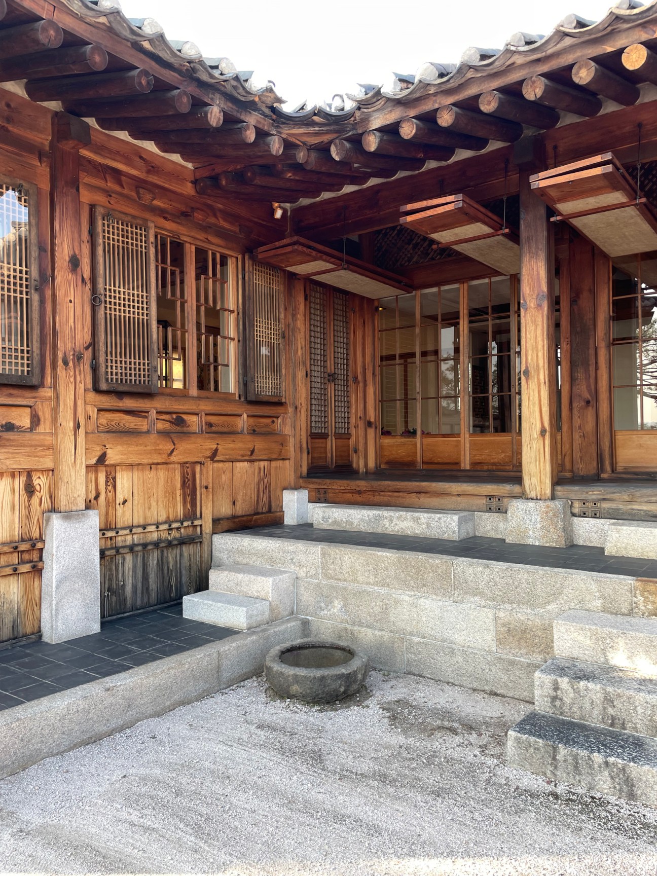Traditional Korean hanok courtyard with wooden architecture, curved tiled roofs, and stone steps