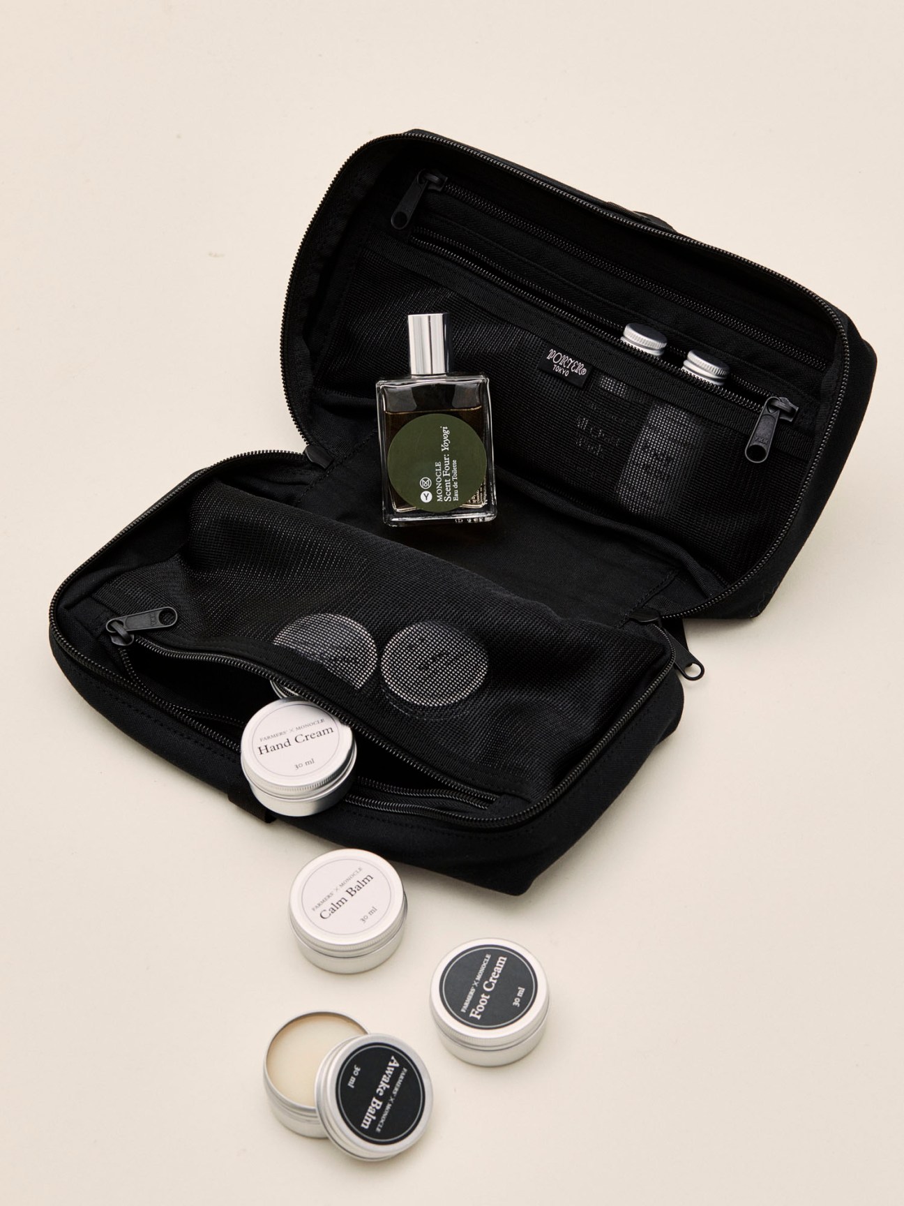 Black toiletry bag opened to show multiple compartments with skincare products and small containers