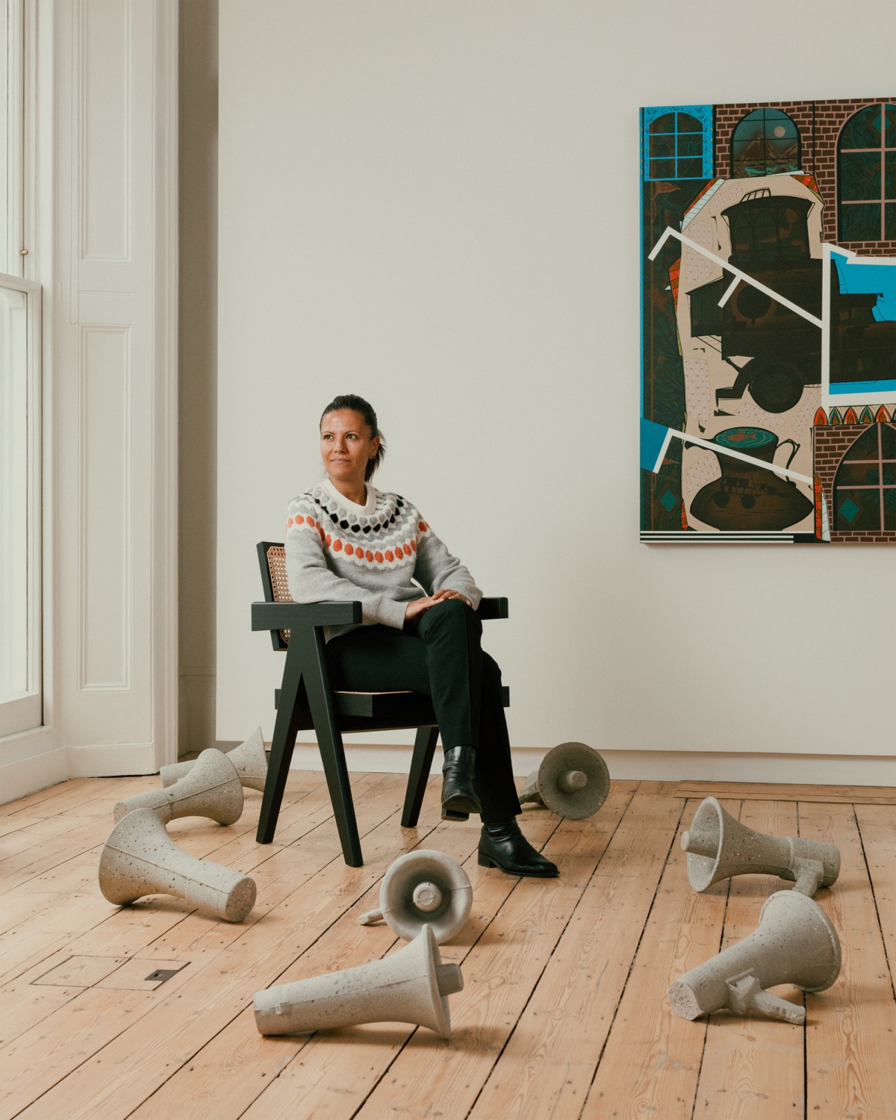 Isabella Icoz of Lehmann Maupin sitting in a chair surrounded by sculptural objects on a wooden floor