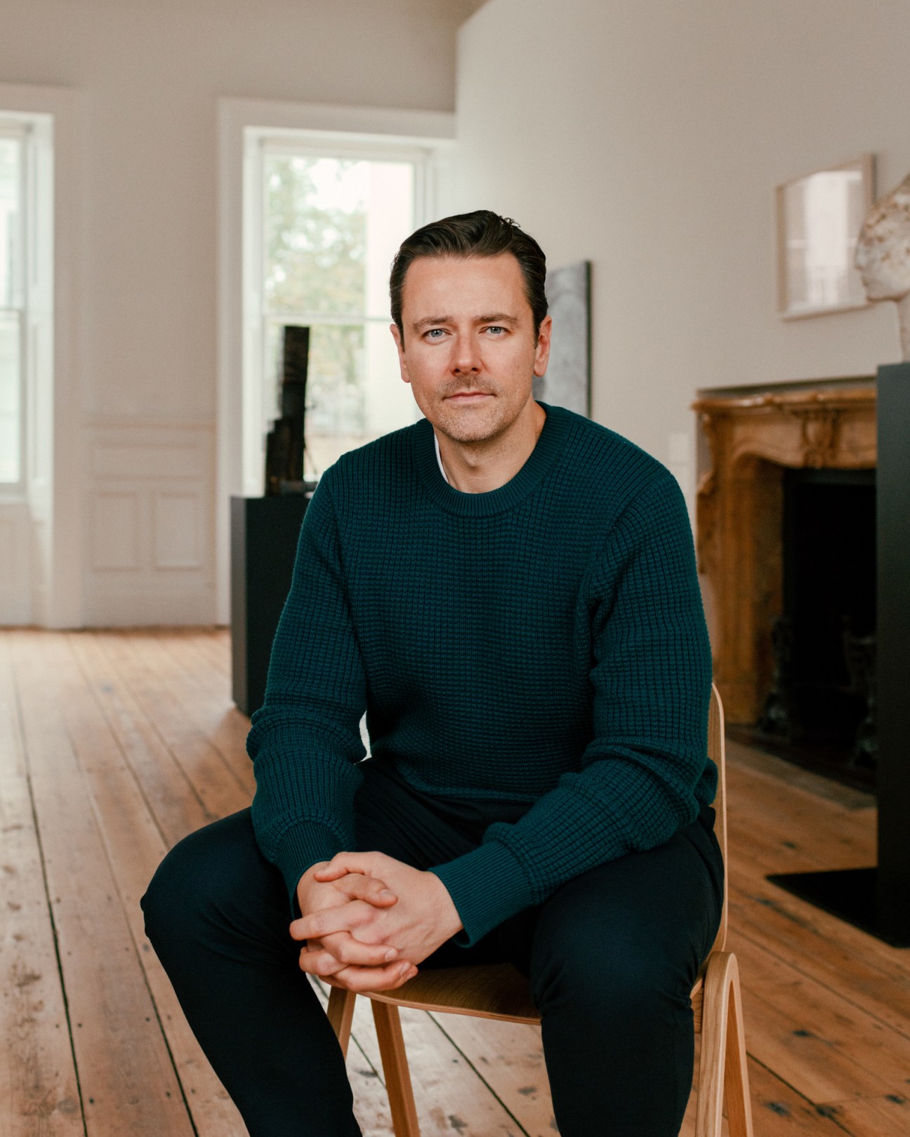 Preston Benson, managing director of Cromwell Place, sitting on wooden chair in bright interior space