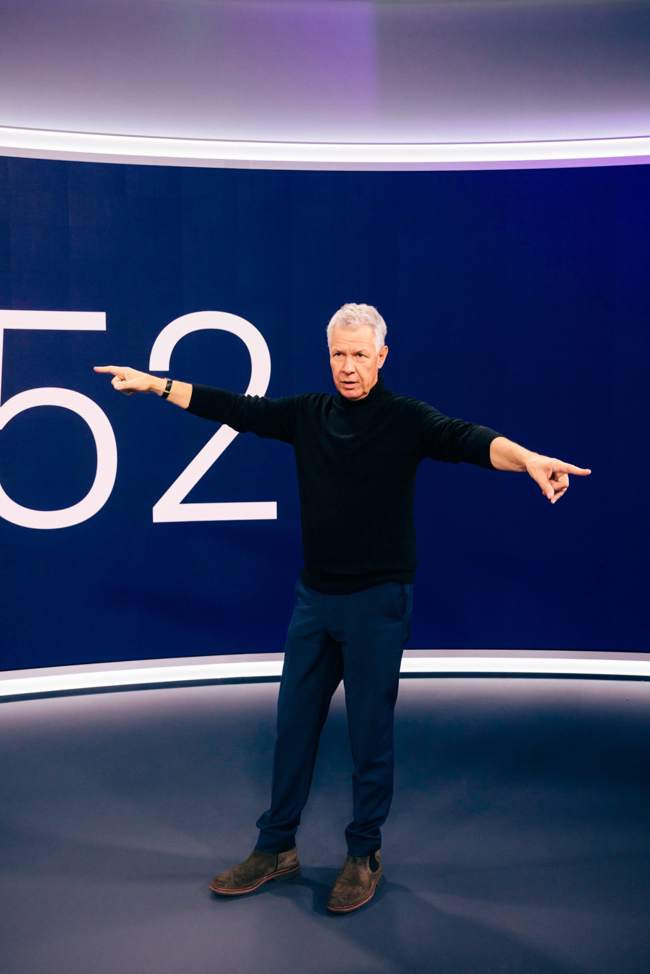 RTL News anchor Peter Kloeppel pointing with both arms outstretched in a television studio
