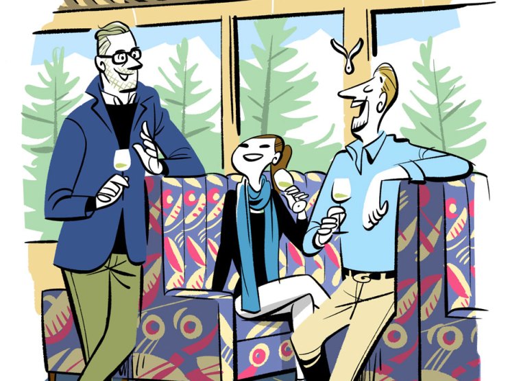 Two men in business casual attire sitting in colorful patterned train seats, holding wine glasses