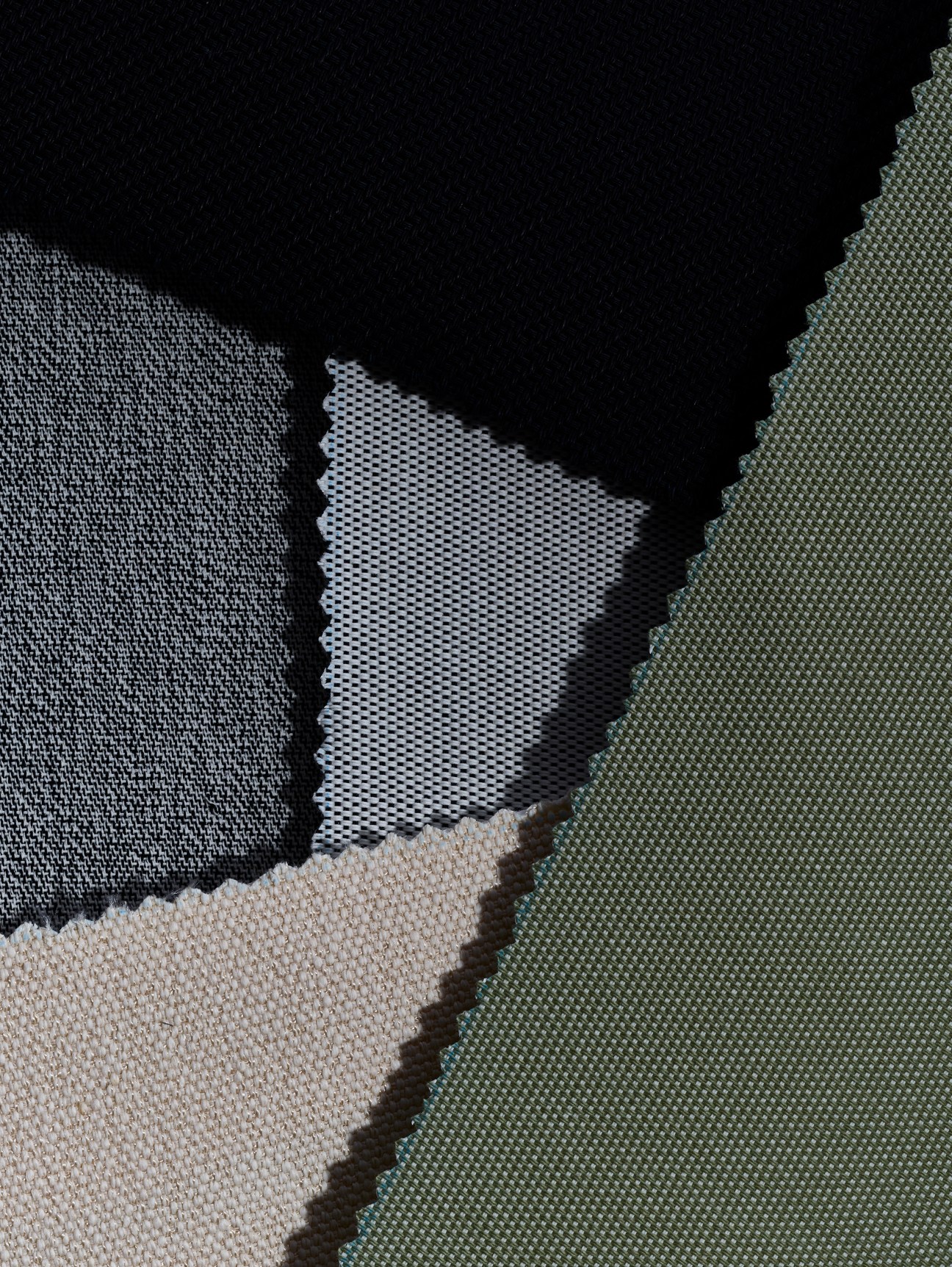 Close-up of various textile fabric samples in different colors and weaves including beige, gray, and green materials