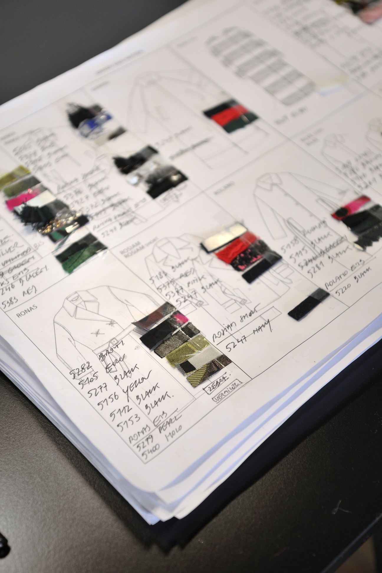 Various fabric swatches and textile samples with handwritten notes arranged on pages in a design studio notebook