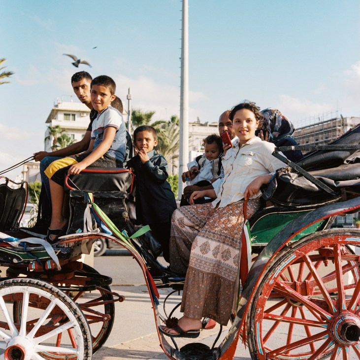 Children and adults riding in colorful horse-drawn carriages in Martyrs' Square, Tripoli