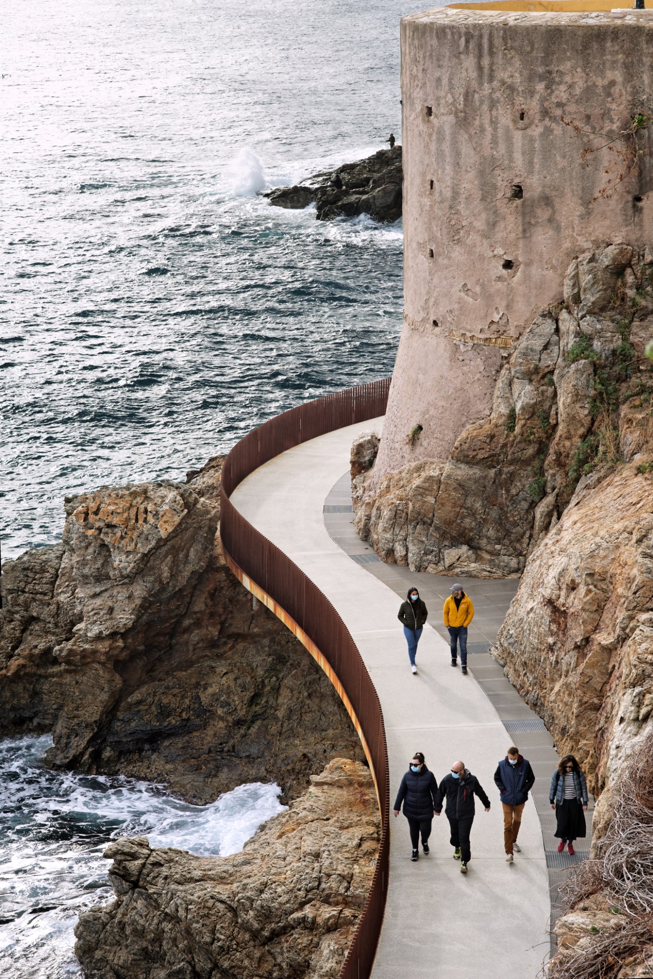 Concrete pedestrian walkway built into cliff face overlooking Mediterranean Sea in Bastia, Corsica