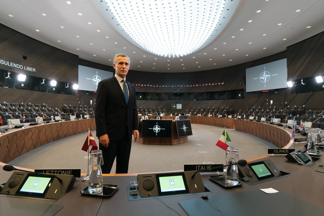 Jens Stoltenberg stands in NATO headquarters conference room with member country flags and desks