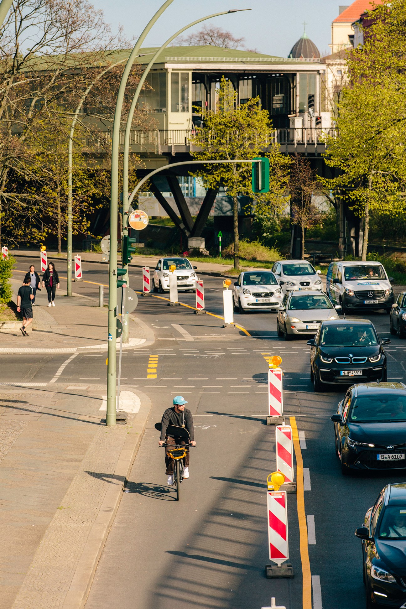 Cyclist riding on a designated bike lane separated from cars by barriers on a Berlin street during lockdown.