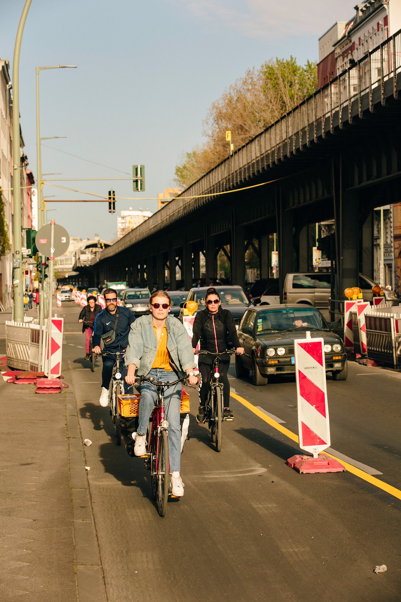 Cyclists ride safely spaced in a dedicated Berlin cycle lane under an overpass during pandemic lockdowns.