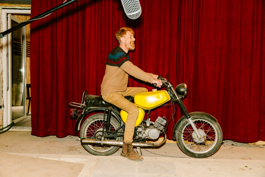 Pete Burgis revving up a yellow motorcycle in a recording studio
