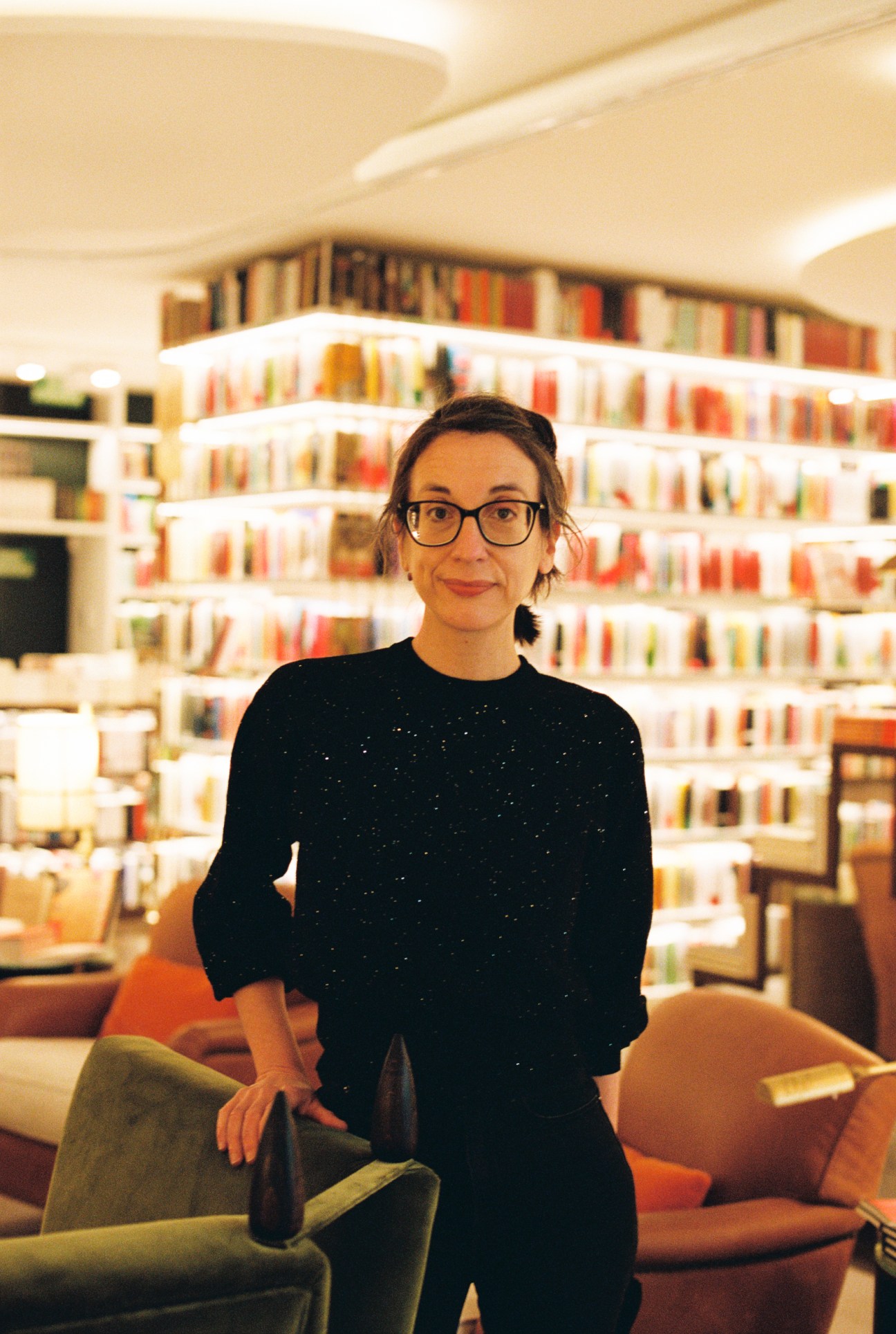 Bookseller Mireya Valencia standing in front of curved bookshelves in a modern bookstore