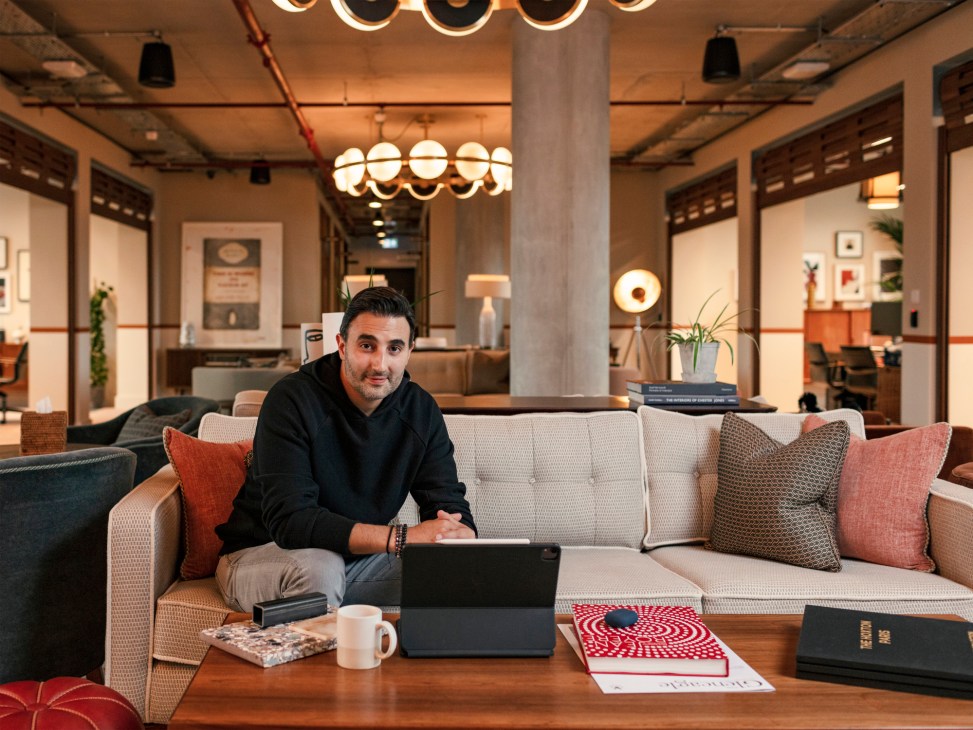 Sharan Pasricha, CEO of Ennismore, sitting on a sofa in a modern co-working space lobby.
