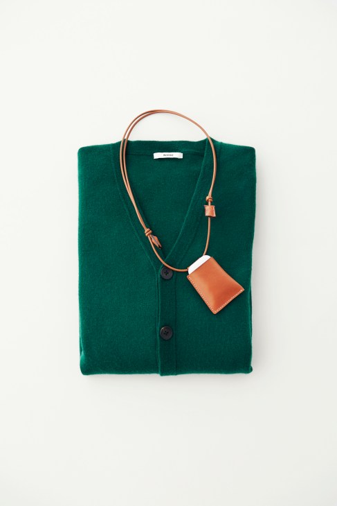 Green cardigan with brown leather strap and small tan AirPods holder by ITTI.
