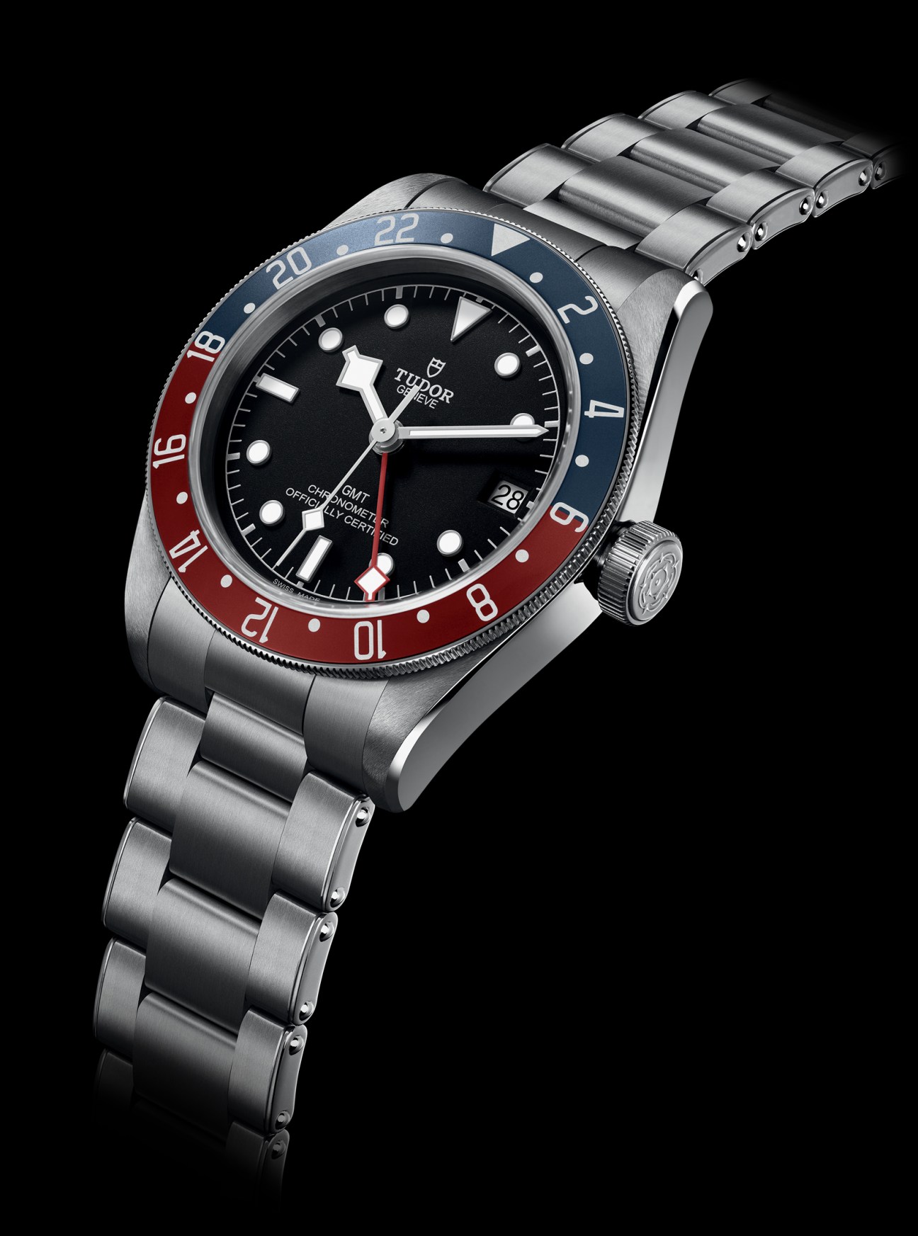 Tudor Black Bay GMT watch with black dial, red and blue bezel, and steel bracelet on black background.