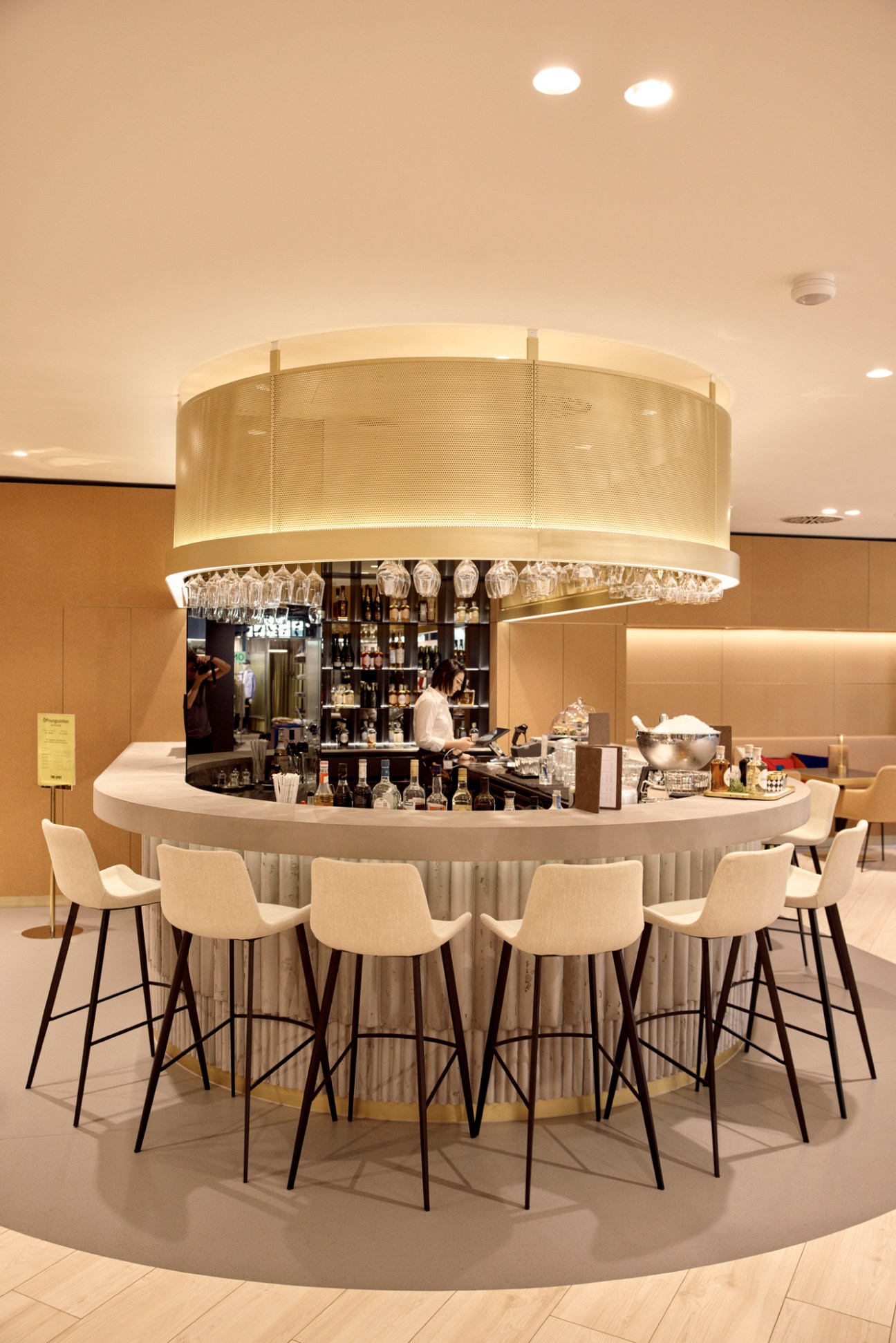 Modern circular bar with pendant lighting and bar stools surrounding white bartender station