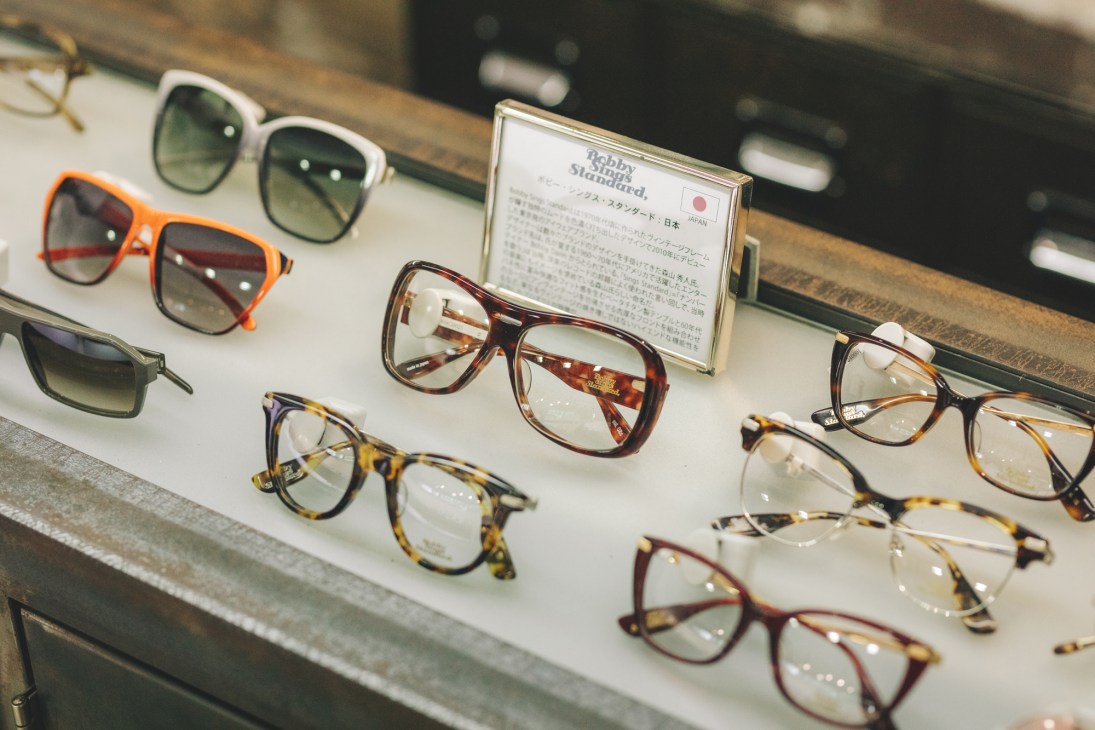 Display case showing various eyeglasses frames arranged on white shelves in an optical shop