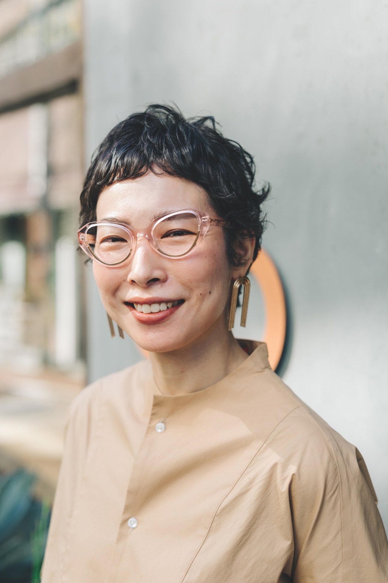 Person wearing clear-framed glasses and geometric earrings in spring eyewear styling