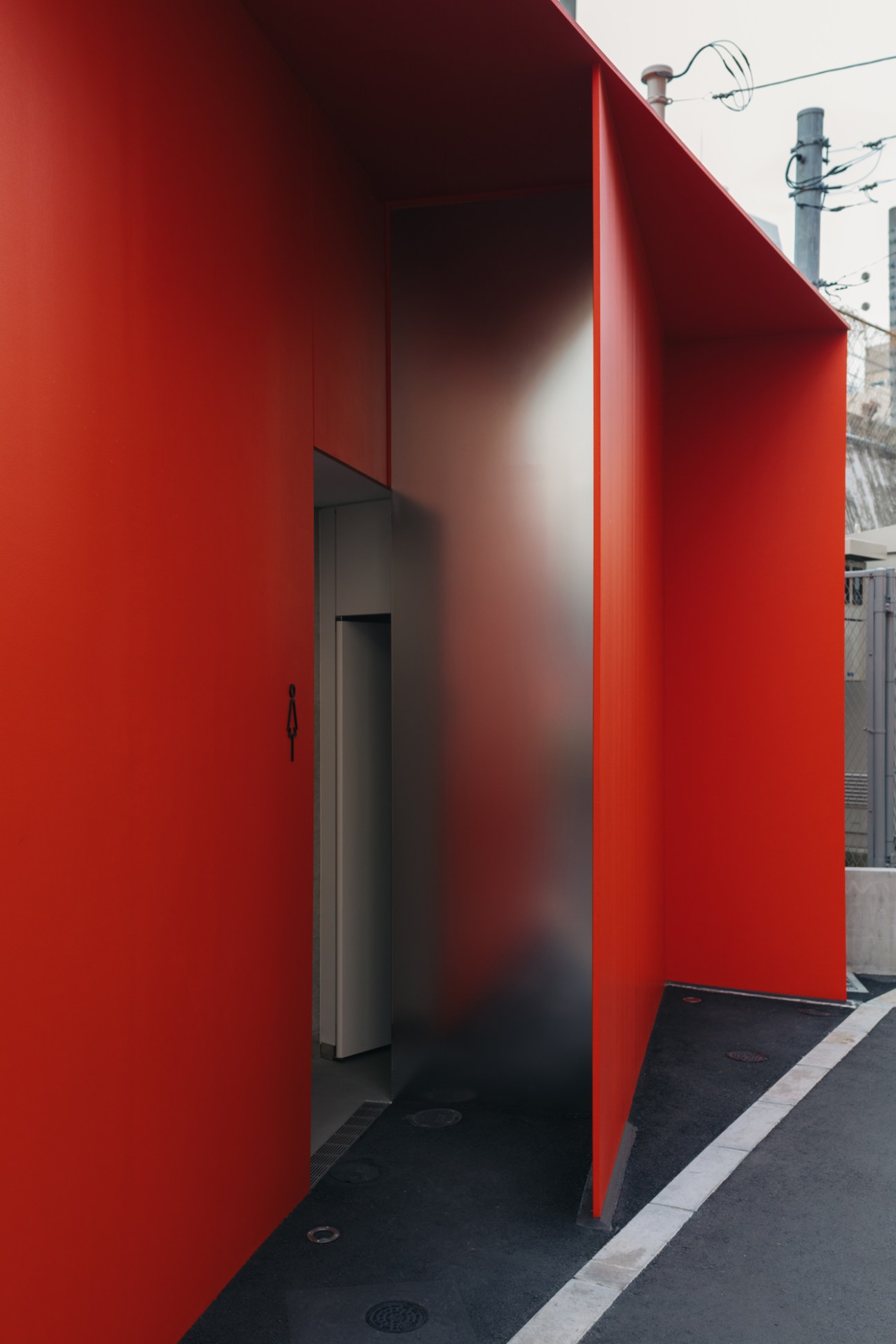 Bright red exterior wall of Nao Tamura's public toilet design with entrance doorway