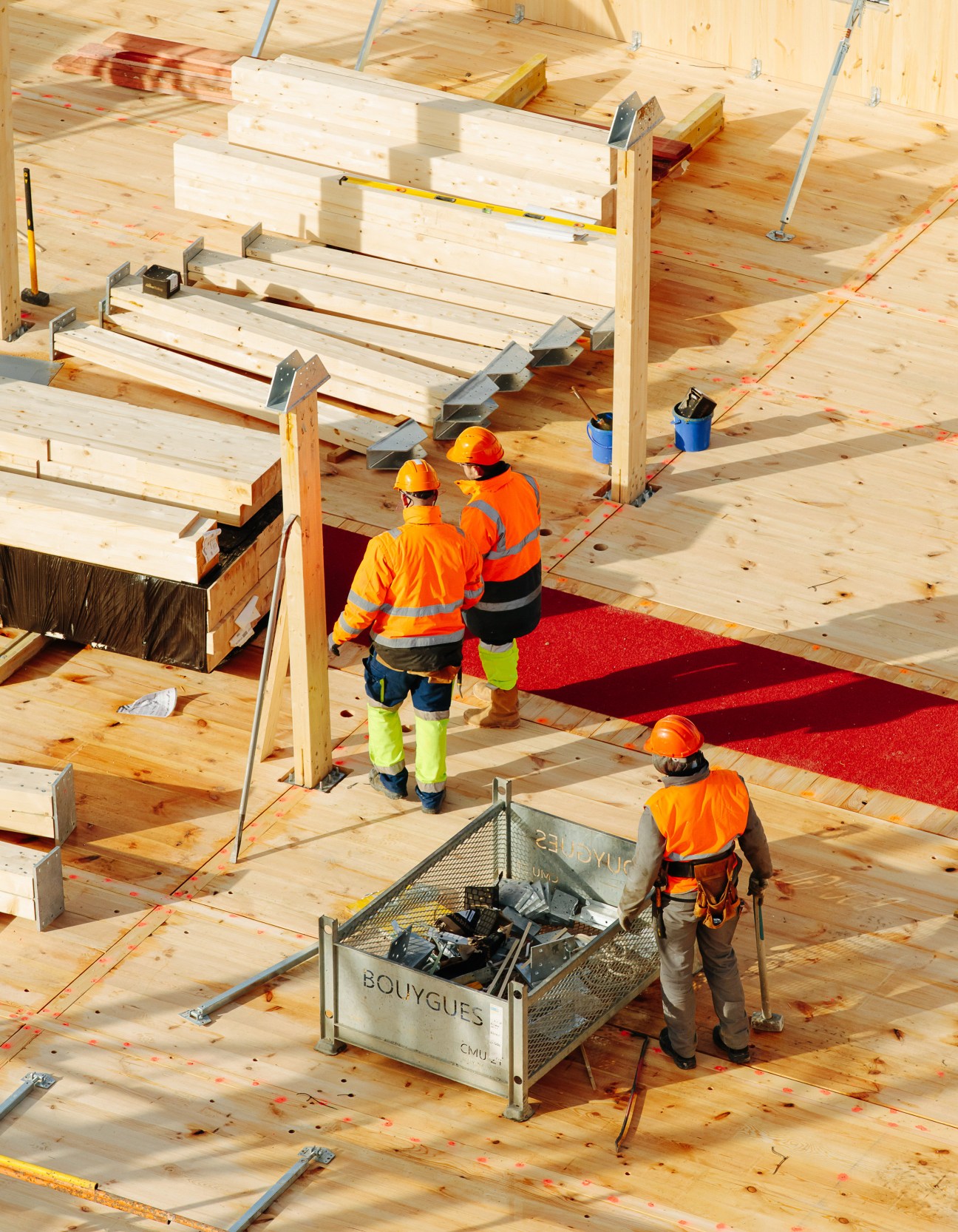 Construction workers in safety gear assembling prefabricated wooden panels on a building site.