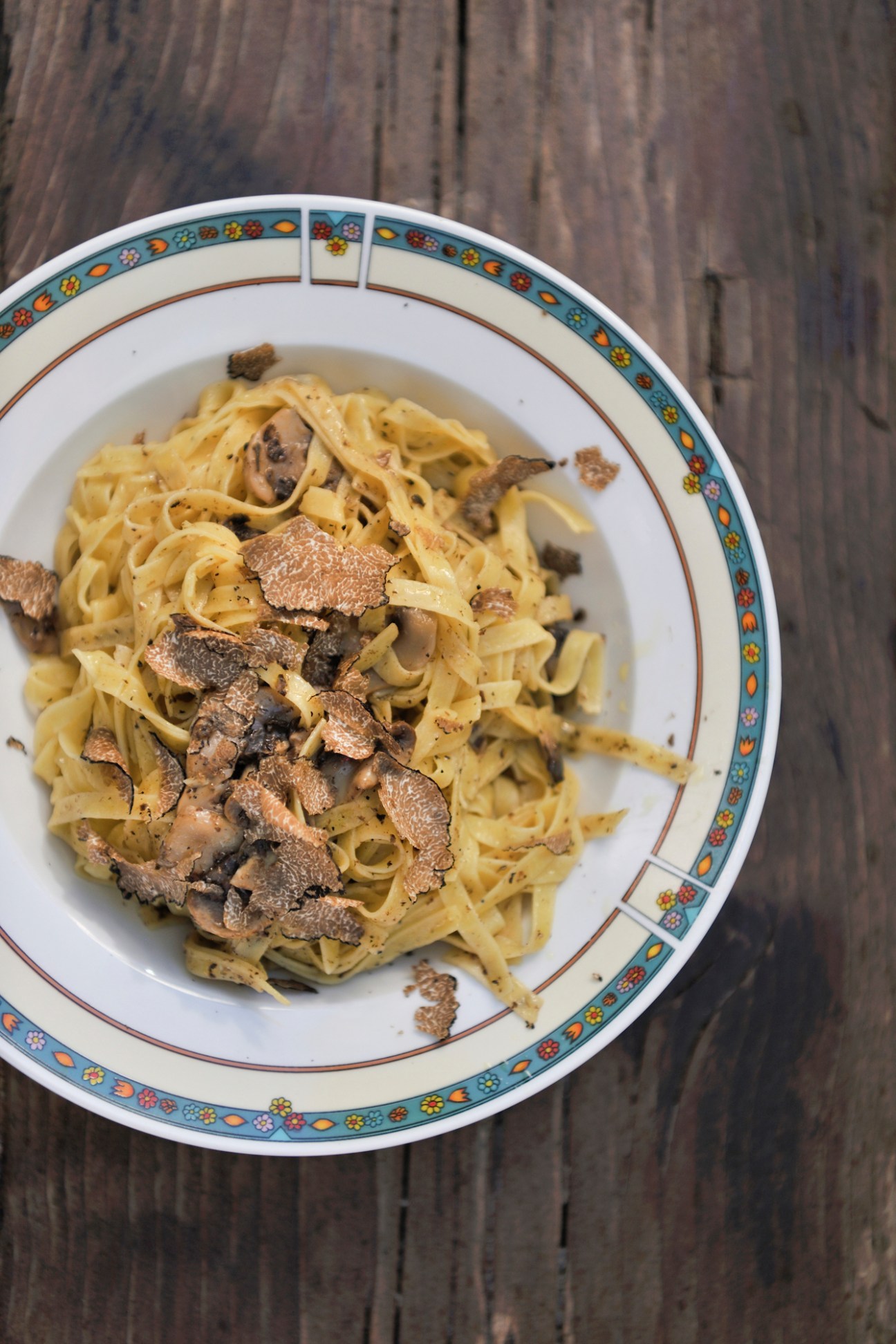Plate of pasta with truffle shavings on decorative ceramic plate