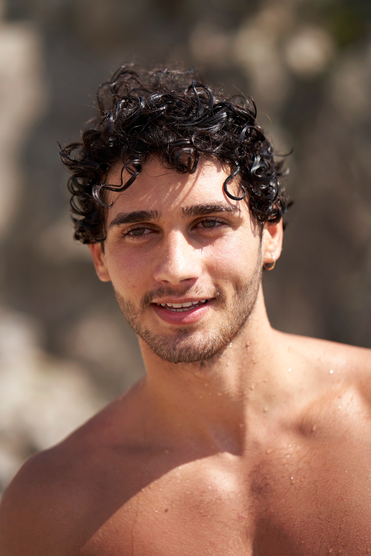 Young man Renato in black swimming trunks preparing to dive from cliffs