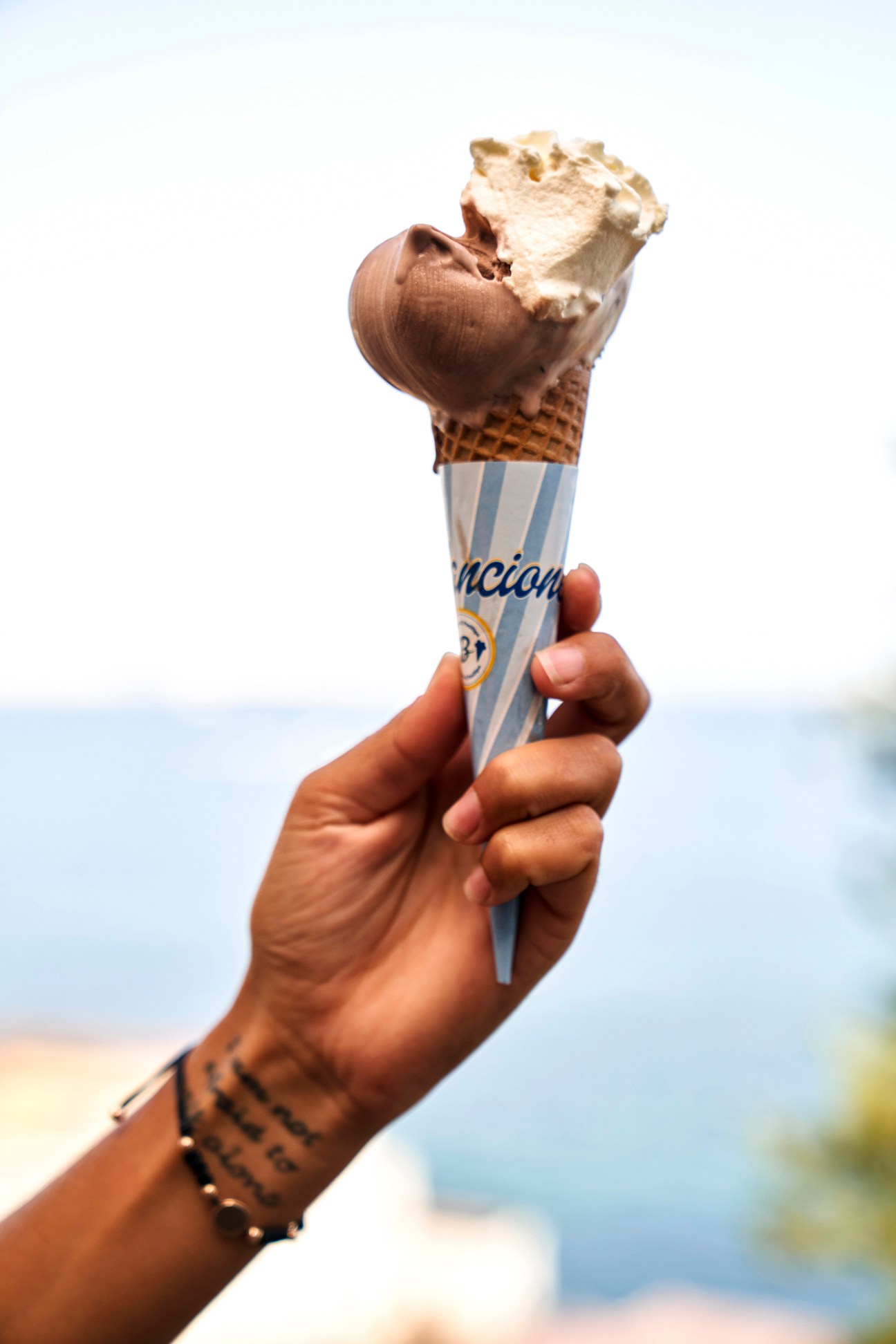 Hand holding ice cream cone with chocolate and vanilla scoops from Bilancione gelateria in Naples