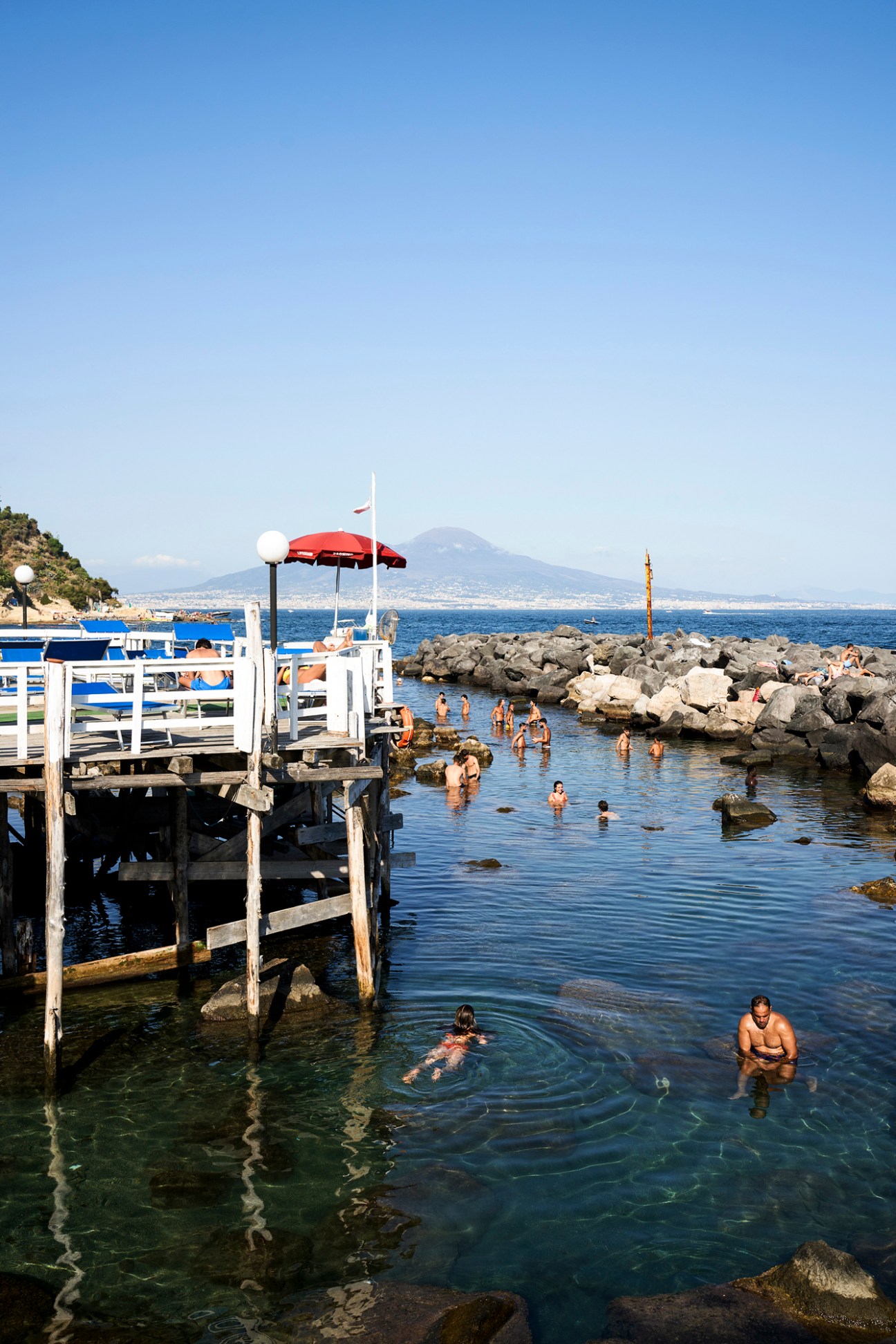 Mount Vesuvius viewed from Naples bay with beach umbrellas in foreground