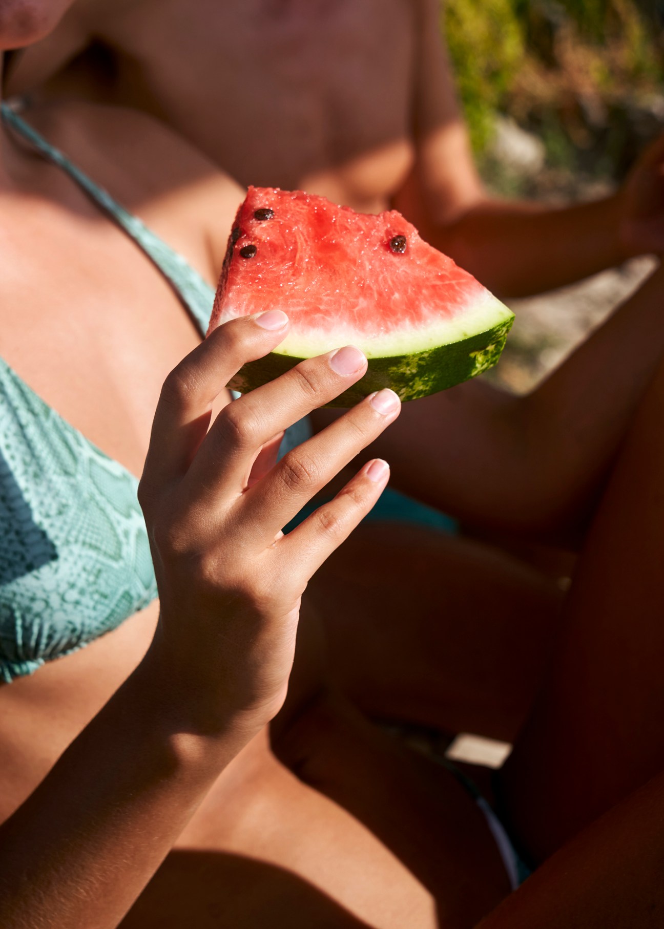 Woman in light blue bikini holding a slice of watermelon at Italian beach